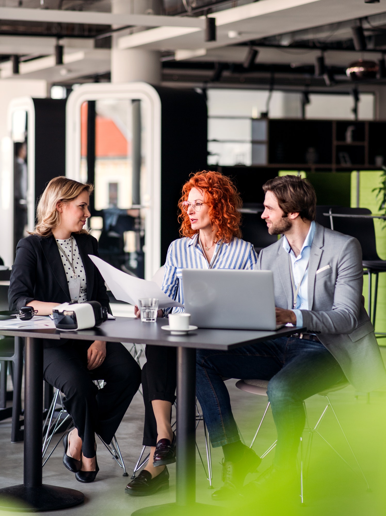 A group of young business people with laptop sitting in an office, talking